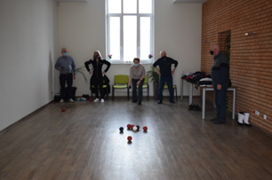 5 osób w sali gra w grę polegajacą na rzucaniu kulami do celu.